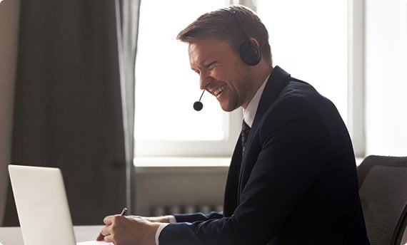 A suited professional sits at a desk, working on a laptop with a headset on - The Law Offices Of Matthew Cargal