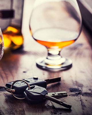 A glass of alcohol and a car key on a table - The Law Offices Of Matthew Cargal