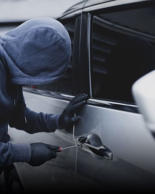 A person in a hoodie opening a car door, possibly involved in theft - The Law Offices Of Matthew Cargal