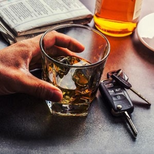 A man holding a glass of whiskey next to car keys