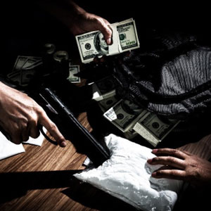 A man holding a gun and money on a table