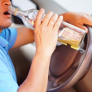 A man is dangerously drinking from a bottle while driving - The Law Offices Of Matthew Cargal